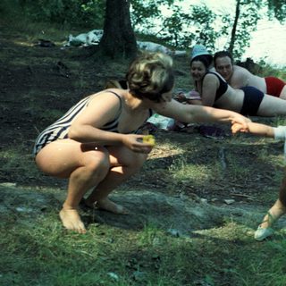 Woman reaches for a toddler near a body of water.