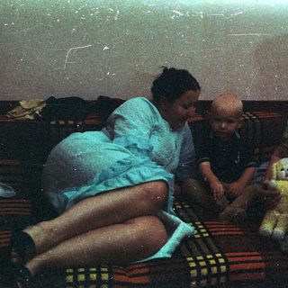 A child sits with two adults on a rug.
