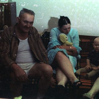 Family portrait featuring a baby, two adults, and a bear.