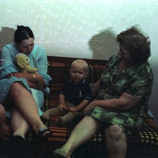 Family portrait featuring a baby, two adults, and a bear.