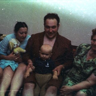 Family portrait featuring a baby being held on a couch.