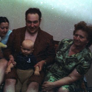Family portrait featuring a baby being held on a couch.