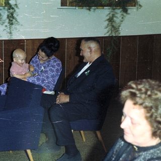 Family seated in chairs, possibly at an event.