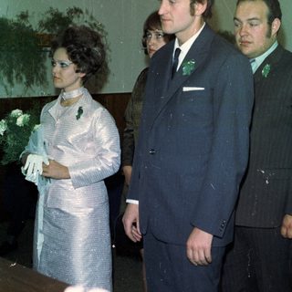 Here's a brief summary of the image: Formal portrait of three people, possibly at a wedding.