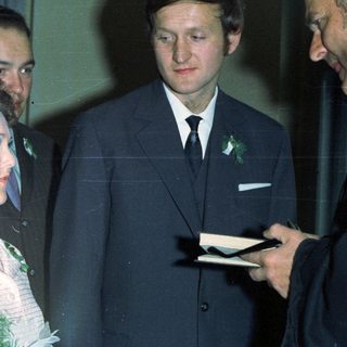 Bride with guests and a man holding a notepad.