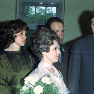 Bride with guests and a man holding a notepad.