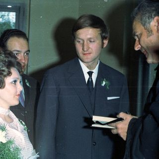 Bride with guests and a man holding a notepad.