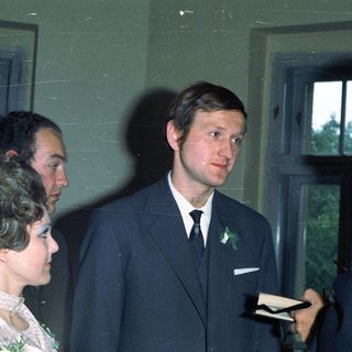 Three people in suits near a window.