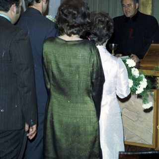 Here's a brief summary of the image: People participate in a religious ceremony near a cross.
