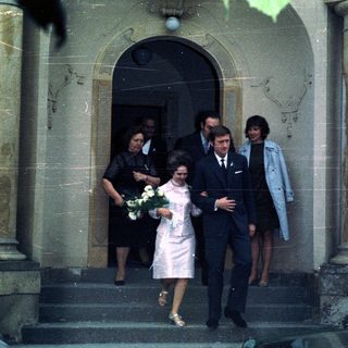 Couple exiting a building, possibly a wedding or formal event.