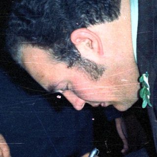 Man signing document, possibly at a formal event.