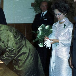 Woman signs document with onlookers during an event.