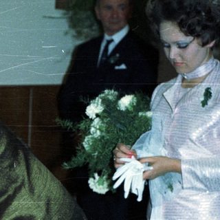 Woman signs document with onlookers during an event.