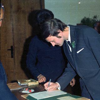 Prince Charles signing a document, likely a marriage certificate.