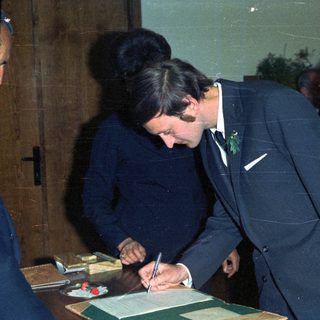 Prince Charles signing a document, likely a marriage certificate.