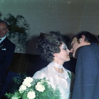 Couple embraces during a wedding, surrounded by guests.