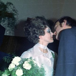 Couple embraces during a wedding, surrounded by guests.