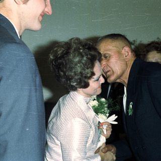 Man embraces a woman in a formal setting.