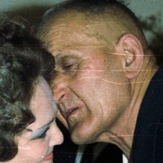 Man embraces a woman in a formal setting.