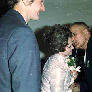 Man embraces a woman in a formal setting.