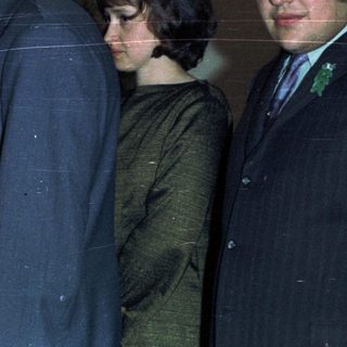 Couple receiving a document, surrounded by well-dressed individuals.