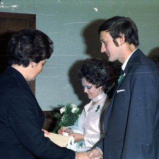 Couple receiving a document, surrounded by well-dressed individuals.