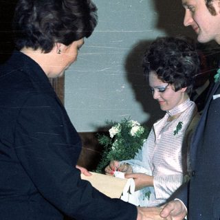 Couple receiving a document, surrounded by well-dressed individuals.
