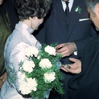Prince Charles receives flowers from a woman during a gathering.