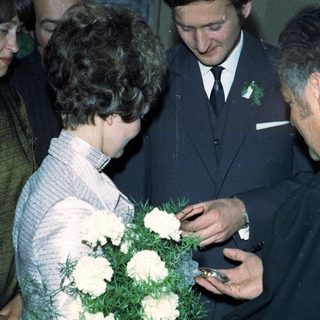 Prince Charles receives flowers from a woman during a gathering.