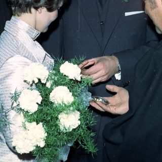 Prince Charles receives flowers from a woman during a gathering.
