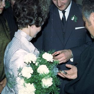 Prince Charles receives flowers from a woman during a gathering.