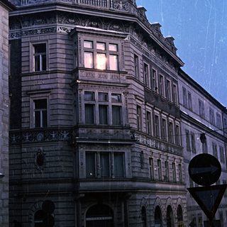 Ornate building at night, illuminated windows, rain visible.