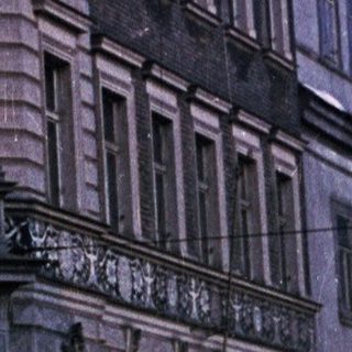 Ornate building at night, illuminated windows, rain visible.