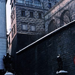 Snowy steps lead to a patterned building and stone arches.