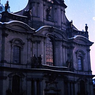 Snow-covered baroque church facade under a twilight sky.