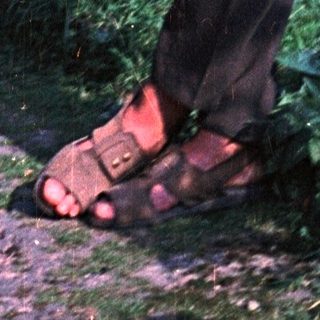 Man in casual wear stands in a garden setting.