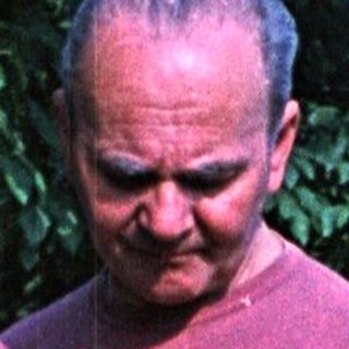 Man in a garden, examining something in his hands.