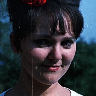 Portrait of a young woman with a red flower in her hair.