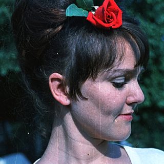 Woman with updo and red rose hair accessory.