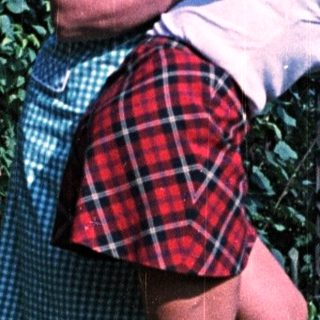 Woman hugs child outdoors, standing by a stone wall.