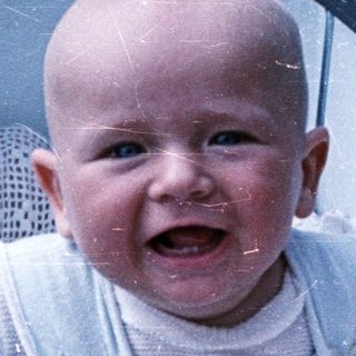 Baby in a stroller smiles, looking directly at the camera.