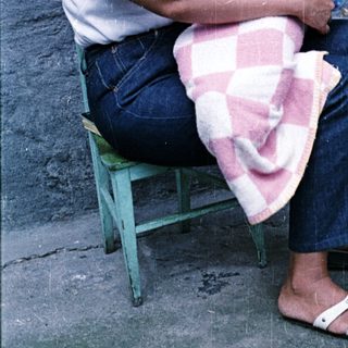 Woman sits with baby, wrapped in a pink blanket.