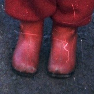Young child stands on a snowy path wearing winter clothing.