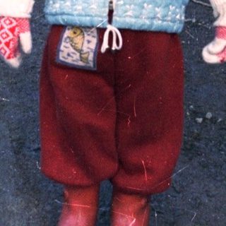 Young child stands on a snowy path wearing winter clothing.