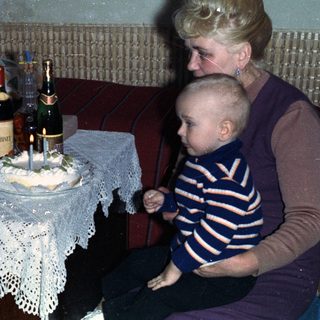 Woman, child, and older woman with a cake and drinks.