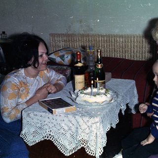 Woman, child, and older woman with a cake and drinks.