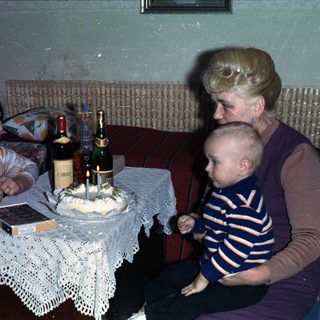 Woman, child, and older woman with a cake and drinks.