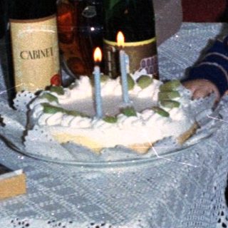 Young child with women celebrating with cake and wine.