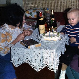 Young child with women celebrating with cake and wine.