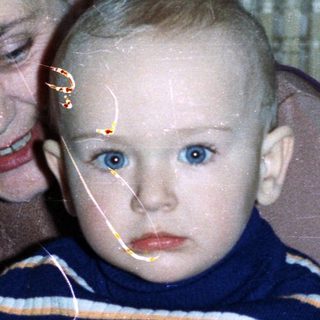 Baby held by woman near birthday cake and drinks.
